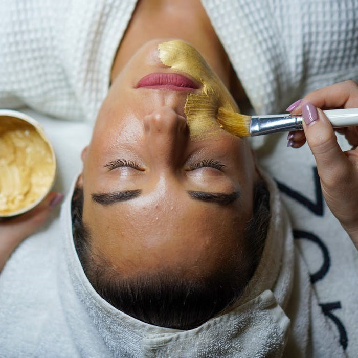  A woman doing a facial mask in a spa using a brush
