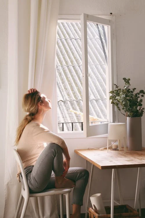 a woman sitting next to a white window