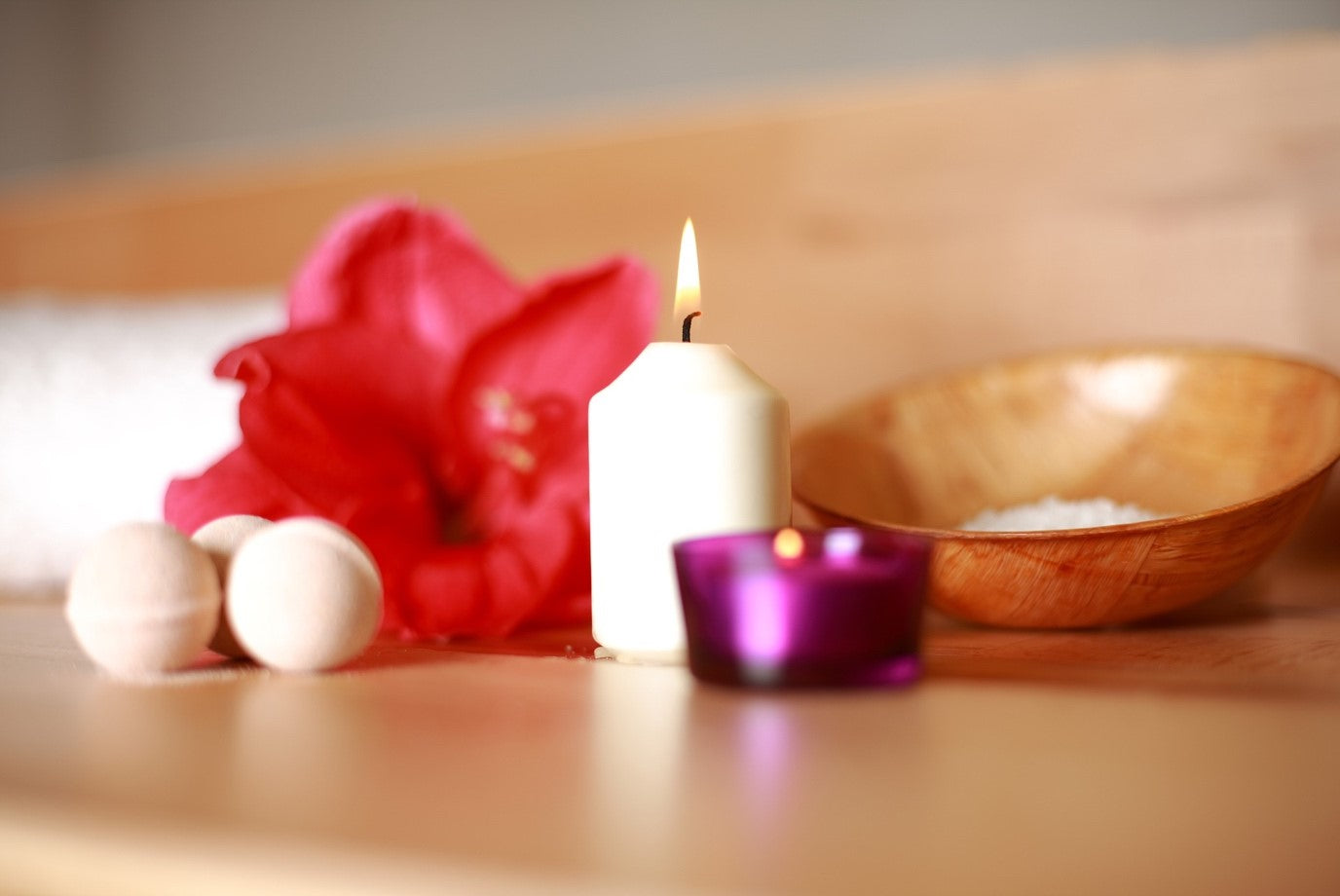 An aesthetic collection of soothing items, including scented candles, bath salts, and flowers