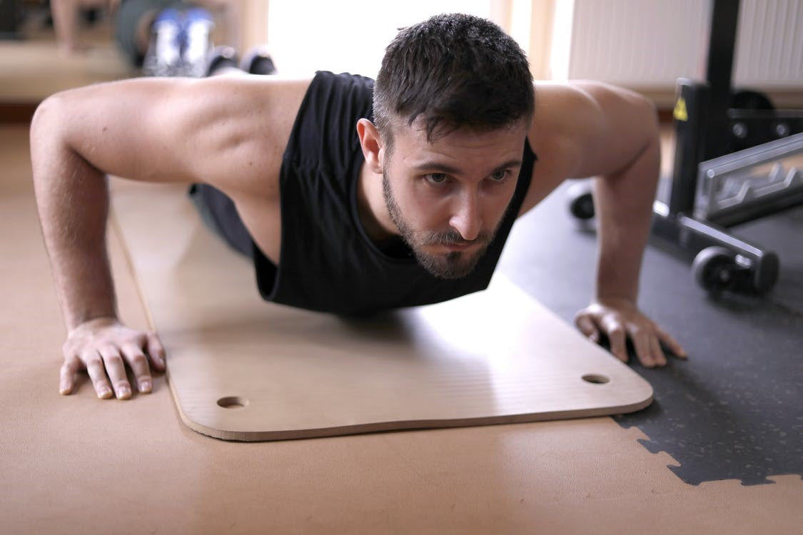 A young and fit man working out on a yoga mat at the gym
