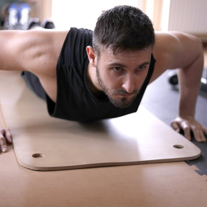 A young and fit man working out on a yoga mat at the gym