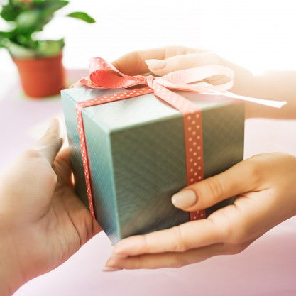 A woman giving a wrapped gift to her friend.