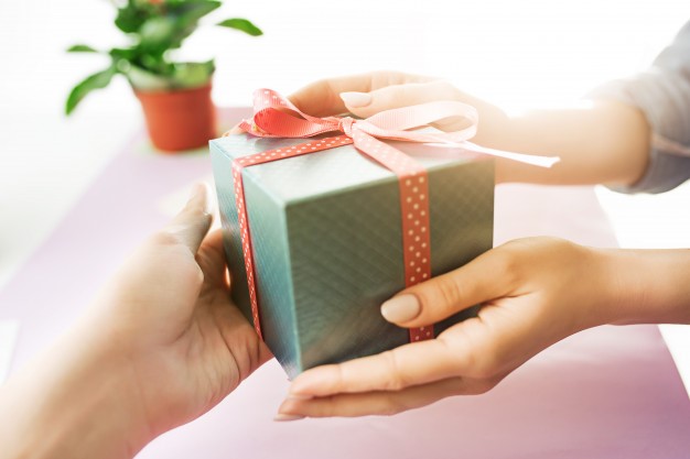 A woman giving a wrapped gift to her friend.
