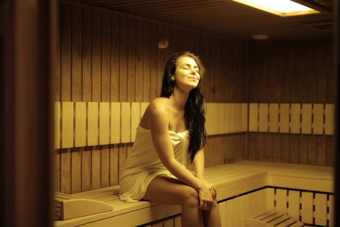 : A happy young woman relaxing in an infrared sauna