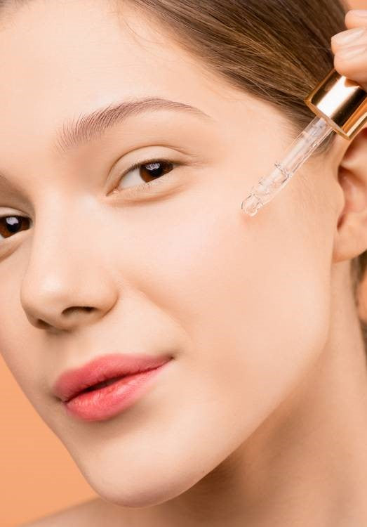 A woman with healthy and fresh skin using a serum.